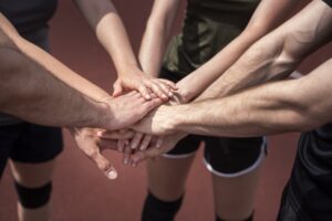 Nahaufnahme von Volleyballspielern, die ihre Hände auf dem Spielfeld als Team-Huddle übereinander legen.